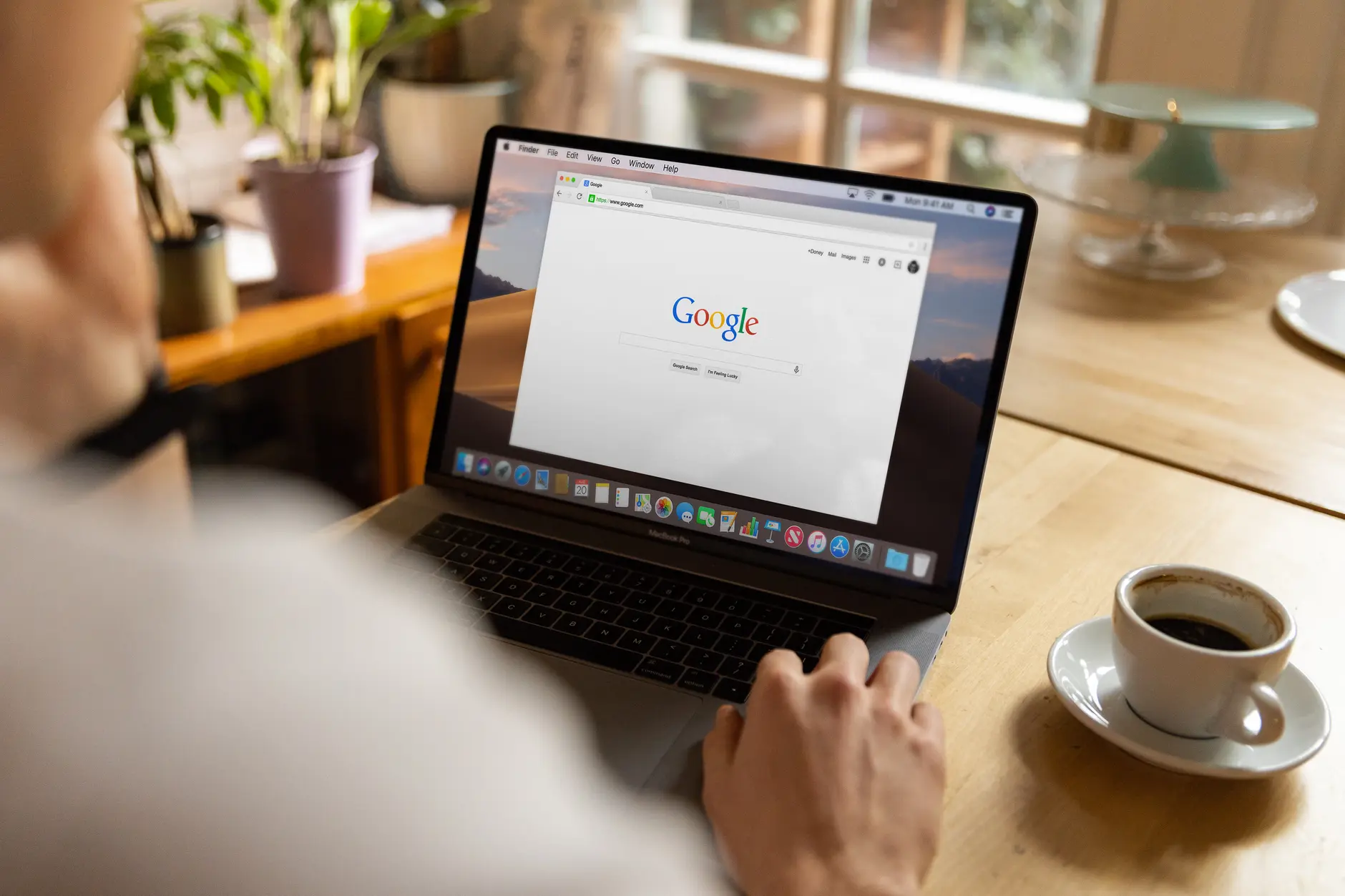 筆電螢幕上開著 Google 搜尋首頁，旁邊放著一杯咖啡